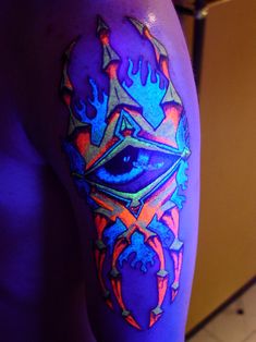 a man's leg with an eye and flames on it in neon blue light