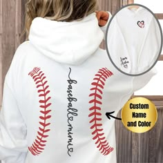 a woman wearing a baseball hoodie with custom name and color on the back, next to a wooden fence