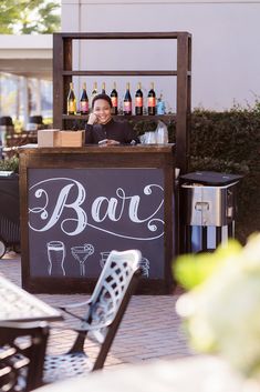 a woman standing behind a bar with bottles on it