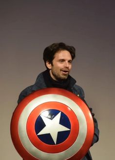 a man holding a captain america shield in his hands