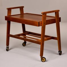 a small wooden table with wheels on the top and bottom shelf, sitting against a white background