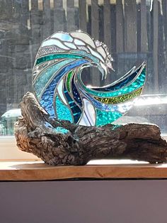 a glass sculpture sitting on top of a piece of driftwood in front of a window