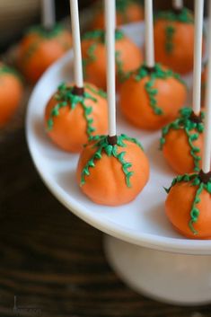 pumpkin cake pops on a white plate with green sprinkles in the middle