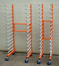 three orange and white hand trucks are next to a garage door with rollers on them