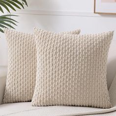 two cream colored pillows on a white couch