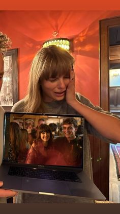 a man and woman are looking at a laptop screen with the image of two women on it