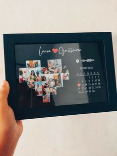 a person holding up a framed photo with the date and year on it in front of a wall