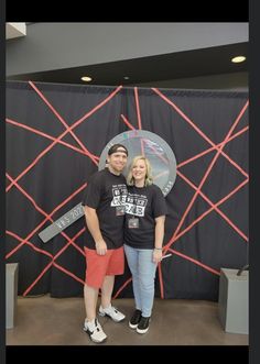 two people standing next to each other in front of a backdrop