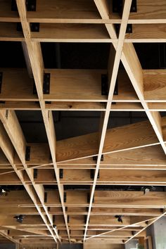 the underside of a wooden structure with multiple beams and wood slats hanging from it's ceiling