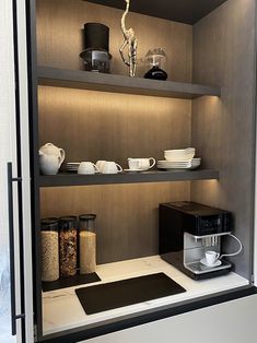 an open cabinet with coffee pots and cups on it, along with other kitchen items