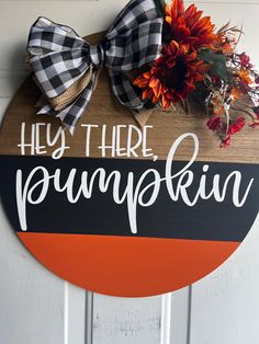 a wooden sign that says hey there pumpkin on it with a bow hanging from the front door