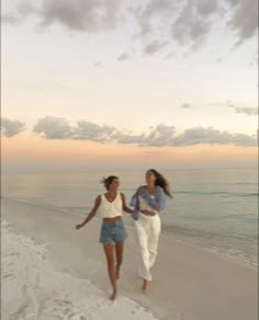 two women running on the beach at sunset