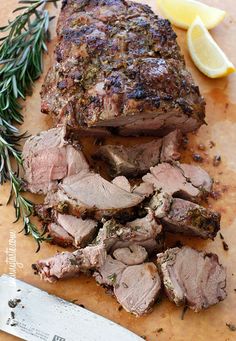 the meat is sliced up and ready to be served on the cutting board with lemon wedges