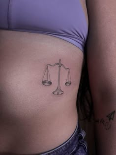 a woman's stomach with a scale and weight tattoo on it