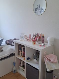 a bedroom with a bed, desk and shelves filled with personal care items on it