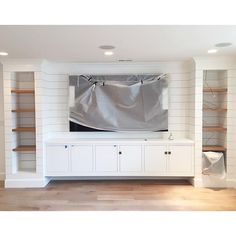 a living room with white walls and shelving units covered in a sheeted cloth