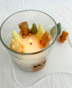 a glass bowl filled with small teddy bears sitting on top of a white table cloth