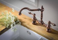 a sink with two faucets and some flowers