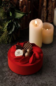 two candles are sitting next to each other on a table with red ribbon around it