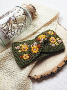 two crocheted bow ties sitting on top of a piece of wood next to a jar