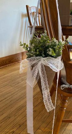 a bouquet of flowers is tied to the back of a wooden chair with white ribbon