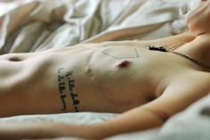 a man laying in bed with tattoos on his chest