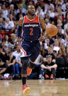 a basketball player dribbling the ball during a game with fans watching from the stands