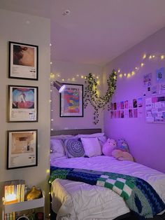 a bedroom with purple walls and pictures hanging on the wall above the bed, along with stuffed animals