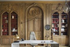 an elegant office with wood paneling and white marble desk in front of bookshelves