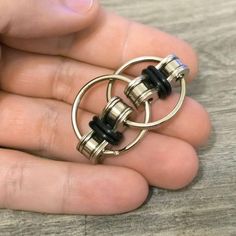 a person is holding two rings in their hand with black beads on the ring,