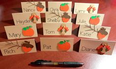 several place cards with pumpkins on them and a pen sitting next to one another