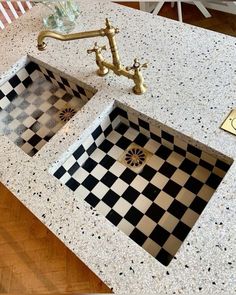 two black and white checkered tiles are on the counter top next to a gold faucet