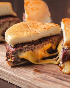 two cheeseburger sandwiches cut in half on a cutting board