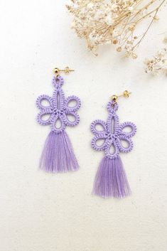 the purple tasseled earrings are adorned with an intricate cross and tassels