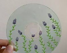 a person holding up a glass plate with flowers painted on the front and side of it