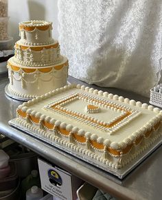 two tiered wedding cakes sitting on top of a metal counter next to each other