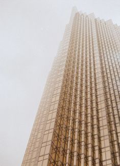 an airplane flying in the air near a tall building with many windows on it's side