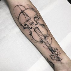 a black and white photo of a violin tattoo on the arm