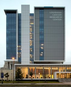 the front of a large building with many windows and lights on it's sides