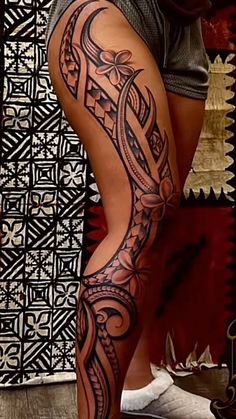 a woman's leg with tattoos on it and an artistic design in the background