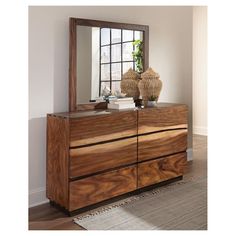 a wooden dresser with a mirror and vase on top