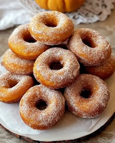 a pile of doughnuts sitting on top of a white plate next to a pumpkin