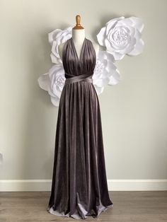 a dress on a mannequin with white flowers in the back and behind it