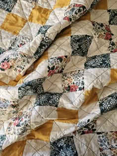 an old quilt that has been made into a blanket with yellow and blue flowers on it