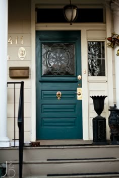 a green door with two black vases sitting on the steps next to it's entrance