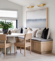 a dining room table with chairs and a bench in front of a large painting on the wall