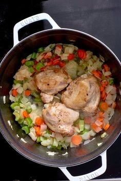 chicken, carrots and celery are cooking in a pot on the stove