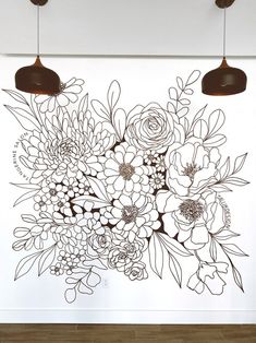 a vase filled with lots of flowers sitting on top of a white wall next to two lamps