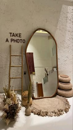 there is a large mirror on the table next to a ladder and vases with flowers