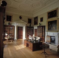 the room has many bookshelves and paintings on the walls